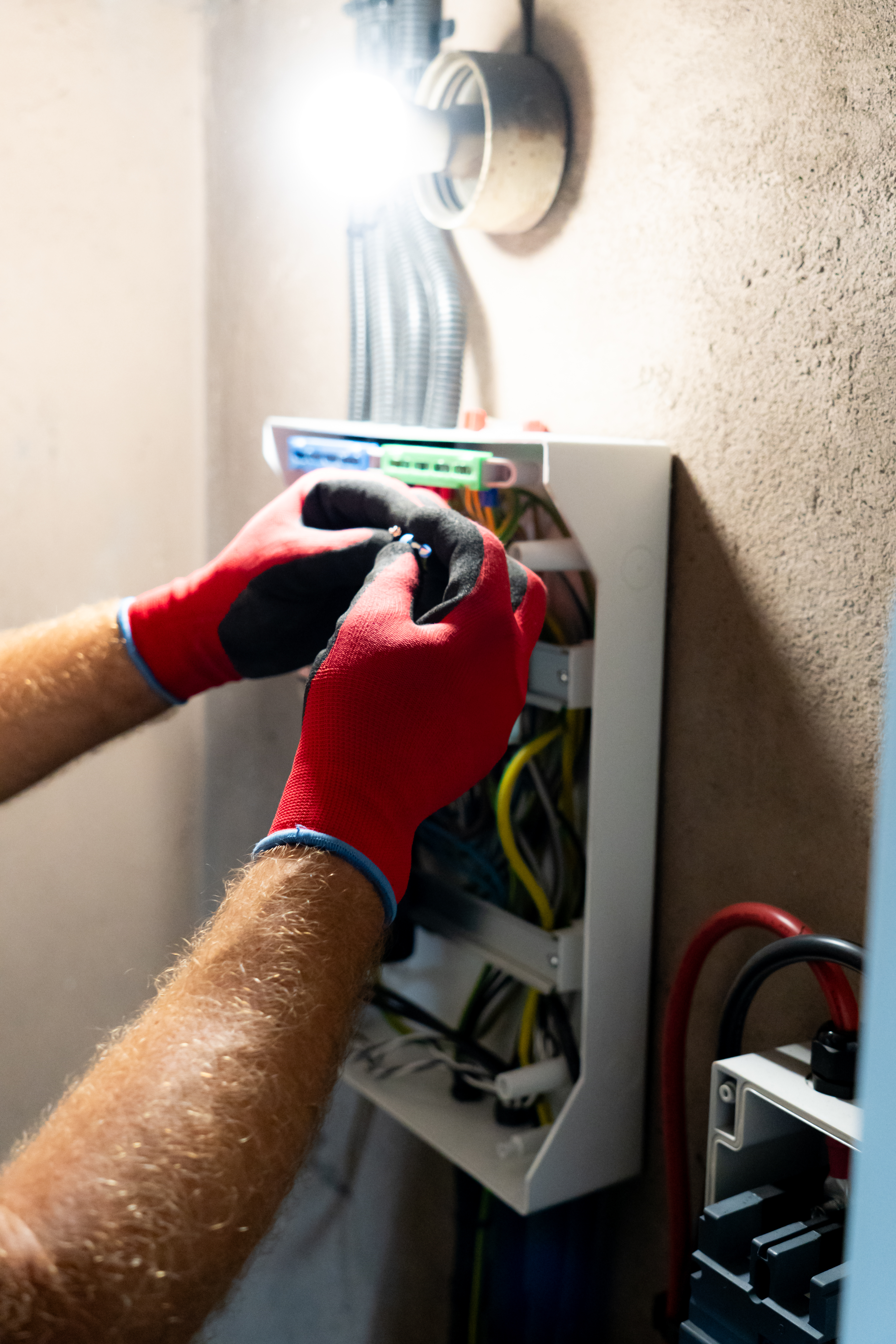 Electrician performing maintenance or installation work inside an electrical panel, ensuring safety and proper electrical connection.